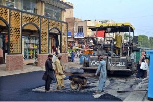 Worker busy in carpeting road at Shaheen Chowk.
