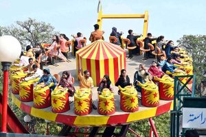 Families enjoy swings at Gulshan-e-Iqbal Park during a recreational outing in the city