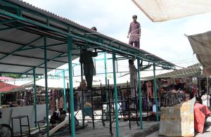 Workers install shade structures over newly rebuilt stalls as reconstruction work continues at the H-9 Weekly Bazaar following the devastating fire that destroyed the market.