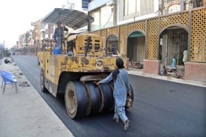 Worker busy in carpeting road at Shaheen Chowk.