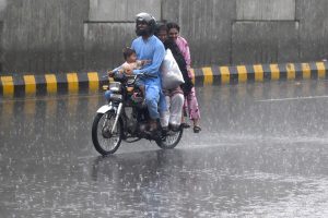 A motorcyclist along with his family members makes his way through heavy rain in the Provincial Capital