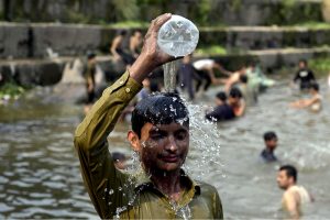 A young man pours water over his head at the Rawal Lake spillway as a large number of youngsters take a dip in the flowing waters to seek relief from the intense summer heatwave gripping the Federal capital.