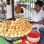 A street vendor prepares and sells freshly fried pakoras and besan naan on Lawrence Road as rainy weather boosts demand for traditional hot snacks