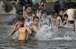 A young man pours water over his head at the Rawal Lake spillway as a large number of youngsters take a dip in the flowing waters to seek relief from the intense summer heatwave gripping the Federal capital.