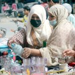 Women purchase kitchen-related items from a street vendor