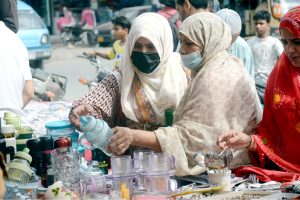 Women purchase kitchen-related items from a street vendor