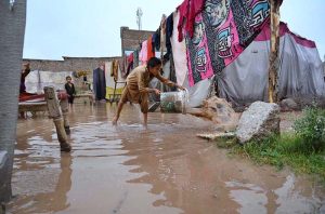 A girl carries a water container on her head while wading through floodwater after heavy monsoon rains inundated a makeshift settlement in the provincial capital.