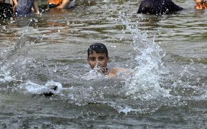 A young man pours water over his head at the Rawal Lake spillway as a large number of youngsters take a dip in the flowing waters to seek relief from the intense summer heatwave gripping the Federal capital.