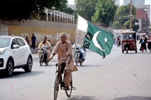 A man rides a bicycle carrying the national flag through the city, expressing his love and patriotism for Country