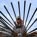A worker assembles a steel reinforcement cage at a construction site during construction work of Kabutar Chowk underpass