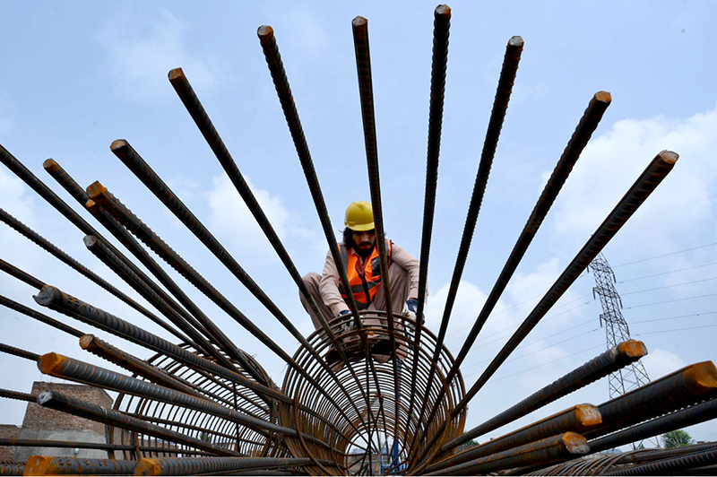 A worker assembles a steel reinforcement cage at a construction site during construction work of Kabutar Chowk underpass