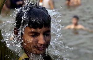 A young man pours water over his head at the Rawal Lake spillway as a large number of youngsters take a dip in the flowing waters to seek relief from the intense summer heatwave gripping the Federal capital.