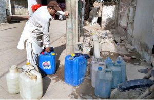 A local resident is filling clean water into their pots from a water tap at Latifabad.