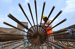 A worker assembles a steel reinforcement cage at a construction site during construction work of Kabutar Chowk underpass