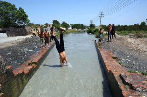 Children cooling off by swimming in a canal during hot weather in the provincial capital.