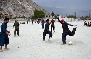 Youngsters play a friendly football match at a local ground in the evening as the majestic mountains and cloudy skies of Gilgit provide a stunning backdrop.