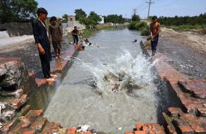 Children cooling off by swimming in a canal during hot weather in the provincial capital.
