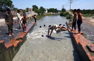 Children cooling off by swimming in a canal during hot weather in the provincial capital.