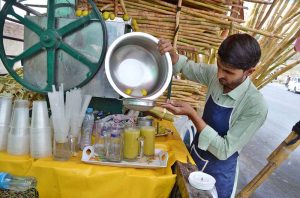 A vendor prepares fresh sugarcane juice for customers as soaring temperatures drive up demand for refreshing drinks at Joint Road.