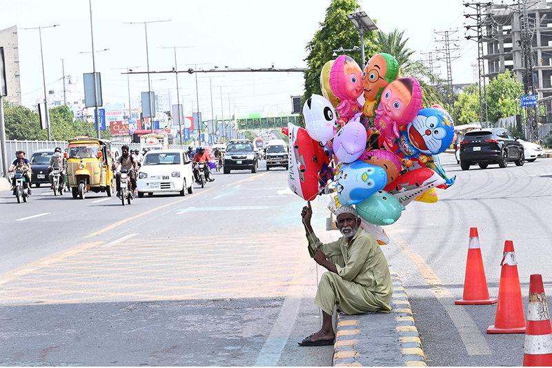 An elderly man is selling balloons on the roadside to earn a living for children, Ferozpur Road