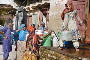 People fill their pots with clean drinking water from a tap at an ice factory in the Makki Shah area