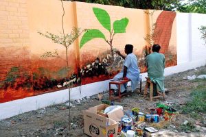 Two artists are creating an eye-catching 'graffiti mural' on a public wall, adding color and creative beauty to the urban landscape.