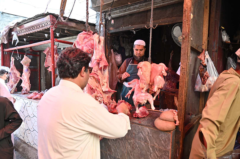 Customers purchase fresh mutton and chicken from a traditional butcher shop in a busy market