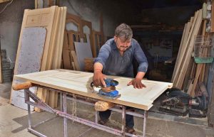 A carpenter makes wooden doors for customers at his workshop on Spiny Road in the provincial capital.