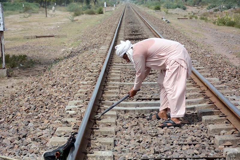 A worker of Pakistan Railways repairs railway track