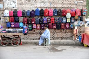 A vendor waiting for customers while selling school bags at Post Office Road.
