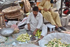 A vendor slices mangoes to prepare pickle at Sabzi Mandi