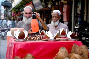 An aged man selling and displaying coconut to attract the customers at Sadar Road. APP/SYR/ABB