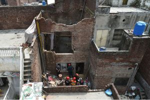 Rescue personnel conduct a search operation amid rubble after the roof of a house collapsed.