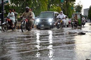 Vehicles pass through stagnant rainwater accumulated at Saddar road after heavy rainfall in the provincial capital