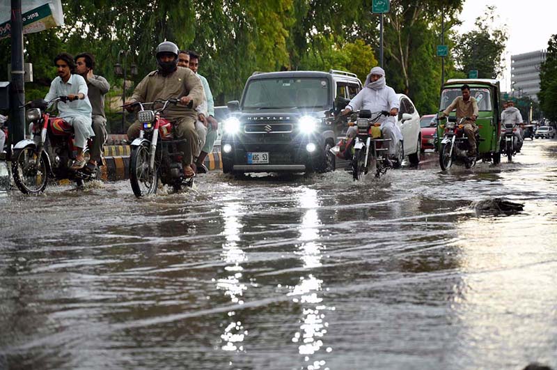 Vehicles pass through stagnant rainwater accumulated at Saddar road after heavy rainfall in the provincial capital