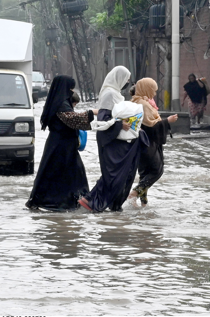 Women make their way through a flooded road following heavy monsoon rainfall on Lawrence Road in the provincial capital