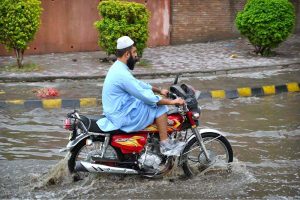 Vehicles pass through stagnant rainwater accumulated at Saddar road after heavy rainfall in the provincial capital