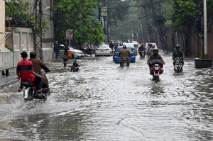 Women make their way through a flooded road following heavy monsoon rainfall on Lawrence Road in the provincial capital