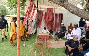 A man weaves a traditional colorful shawls on a pit loom under the shade of a tree during the closing ceremony of the 283rd Urs celebrations of Hazrat Shah Abdul Latif Bhittai.