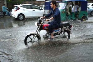 Vehicles pass through stagnant rainwater accumulated at Saddar road after heavy rainfall in the provincial capital