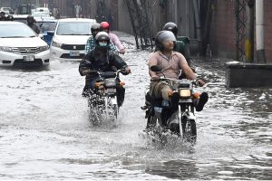 Women make their way through a flooded road following heavy monsoon rainfall on Lawrence Road in the provincial capital