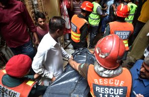 Rescue personnel conduct a search operation amid rubble after the roof of a house collapsed.