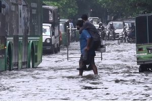 Women make their way through a flooded road following heavy monsoon rainfall on Lawrence Road in the provincial capital