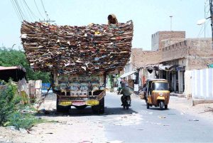 A man on the top of an over-loaded truck with empty carton boxes, passing through on Bahawalpur Road that may cause any mishap and needs the attention of concerned authorities