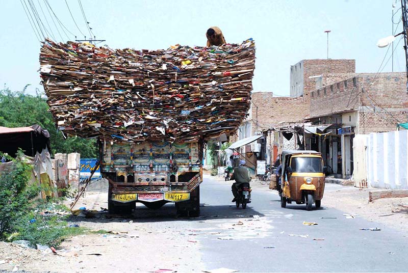 A man on the top of an over-loaded truck with empty carton boxes, passing through on Bahawalpur Road that may cause any mishap and needs the attention of concerned authorities