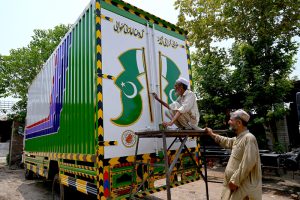 Truck art painter busy in giving final touches to a Pakistani flag on a delivery truck at his workplace on Ring road