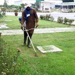 A gardener trimming grass in the lawn of a private institution