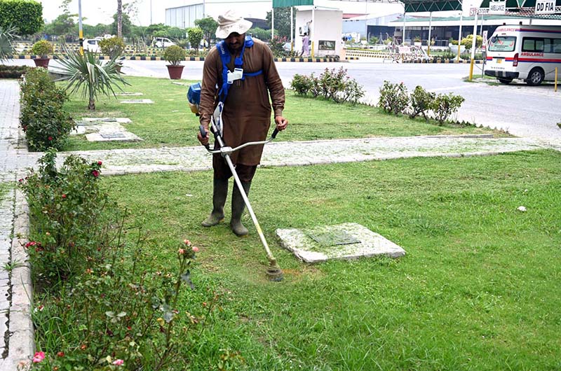 A gardener trimming grass in the lawn of a private institution