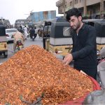 A customer purchases dried apricots from a roadside vendor at Meezan Chowk in the provincial capital