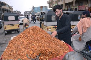 A customer purchases dried apricots from a roadside vendor at Meezan Chowk in the provincial capital